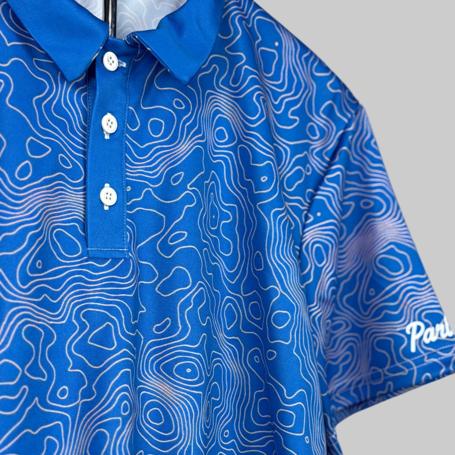 Blue polo shirt with white pattern on a plain background
