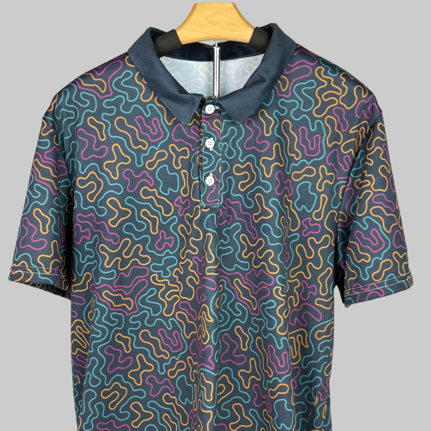 Short-sleeve shirt with a colorful pattern on a wooden hanger against a white background
