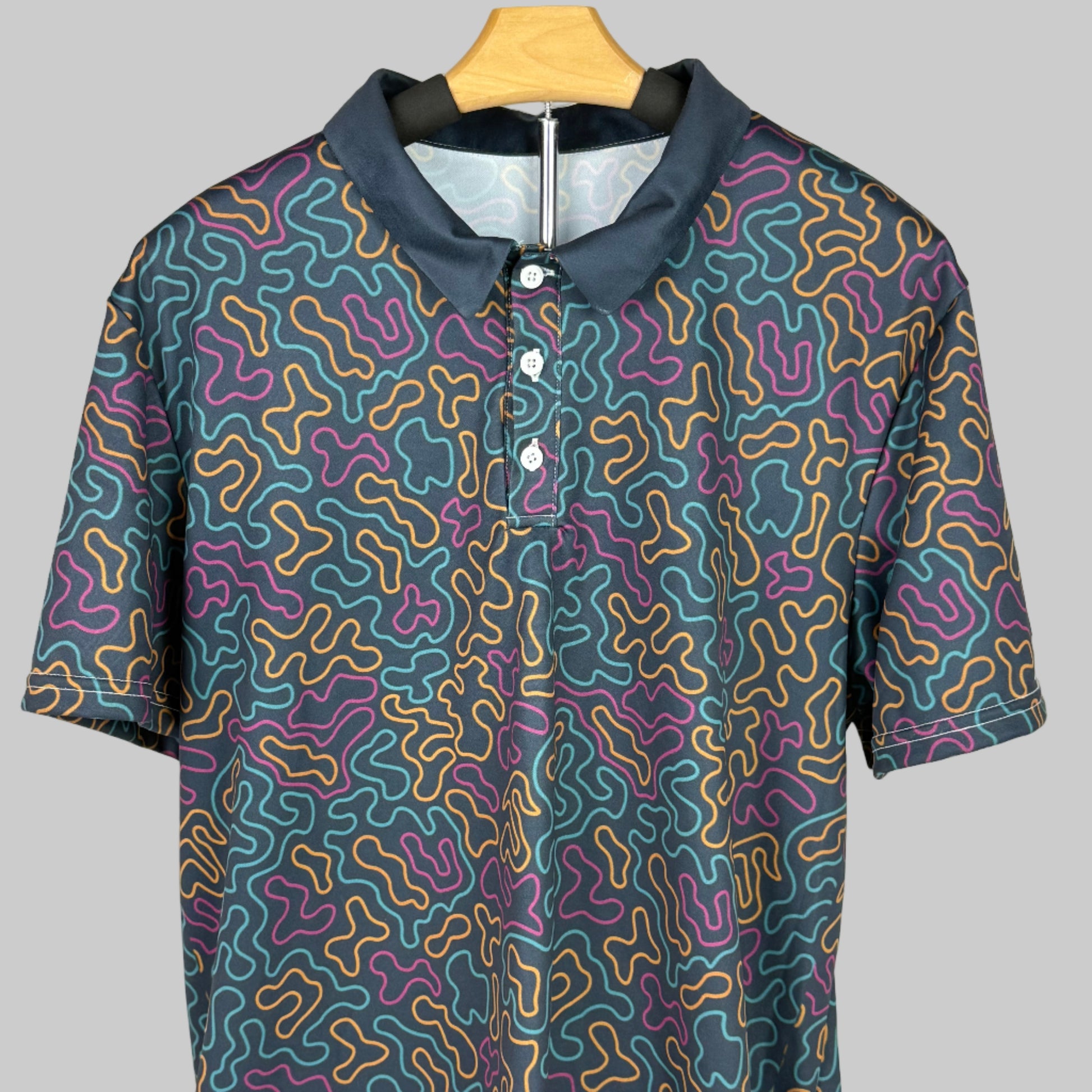 Short-sleeve shirt with a colorful pattern on a wooden hanger against a white background