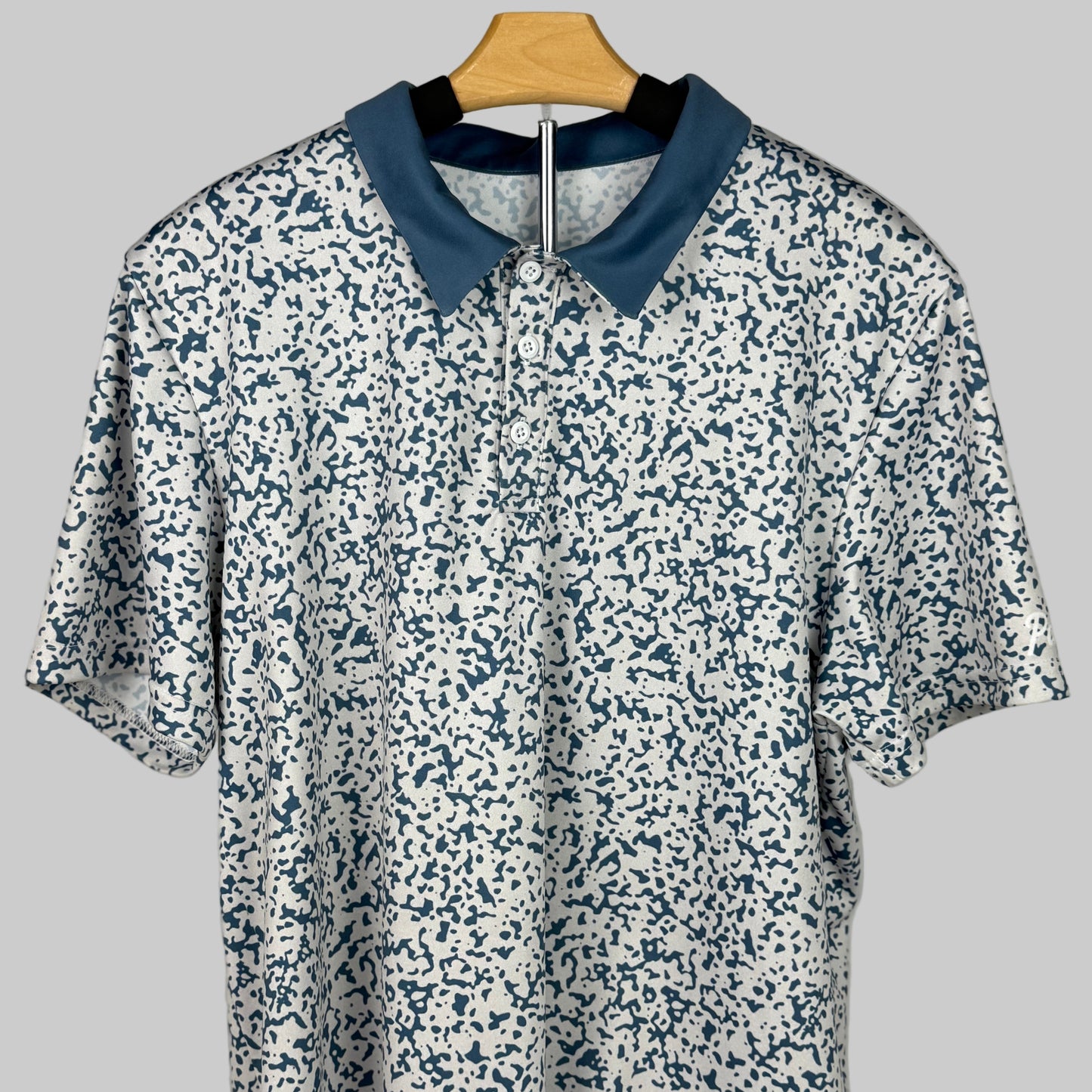 Floral-patterned shirt with blue collar on a hanger against a gray background