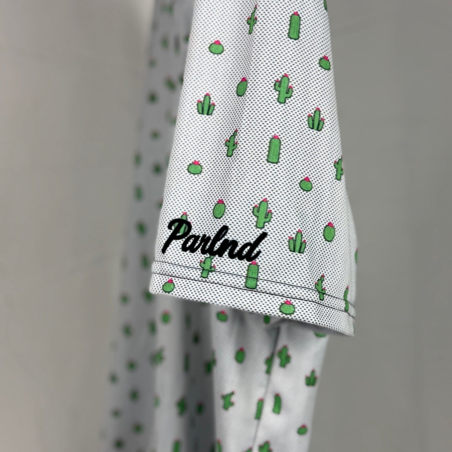 White garment with green cactus pattern and 'Parlnd' branding on a plain background