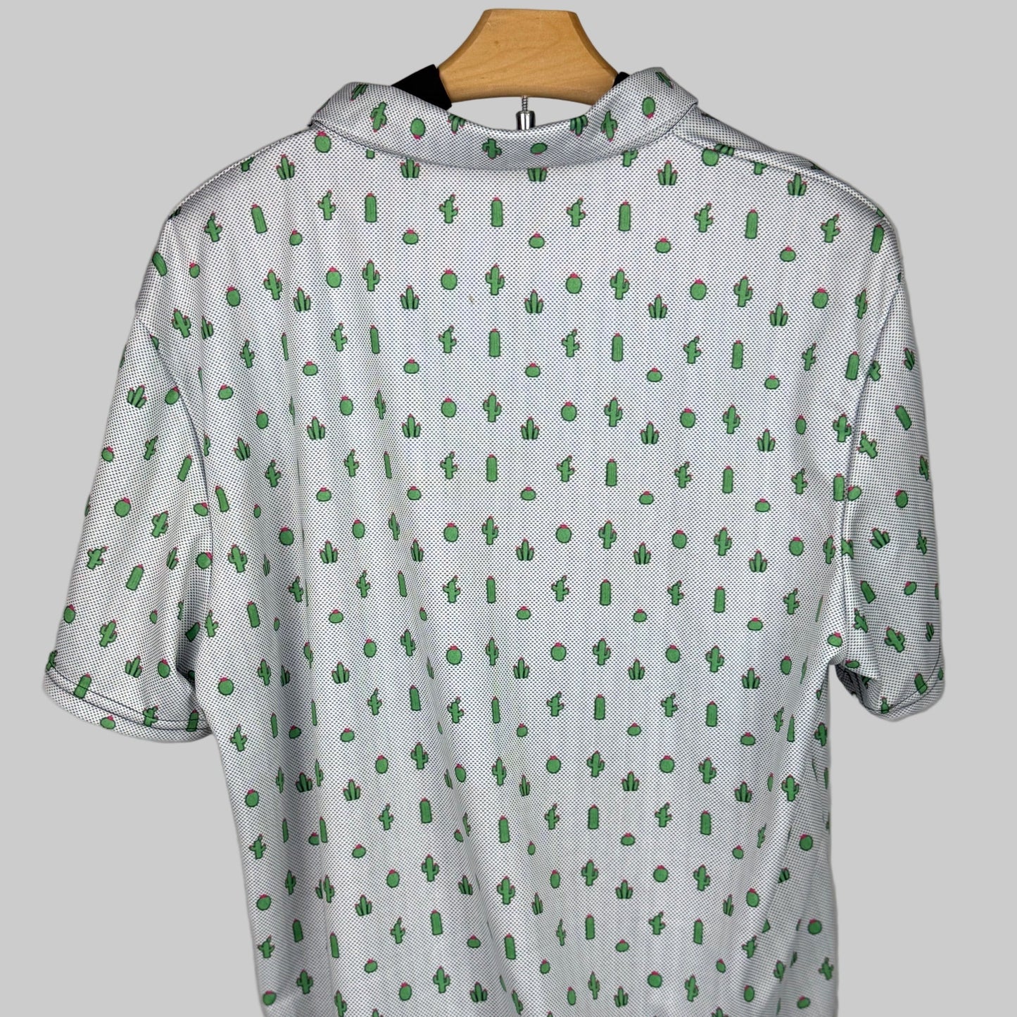 White shirt with green pattern on a wooden hanger against a white background