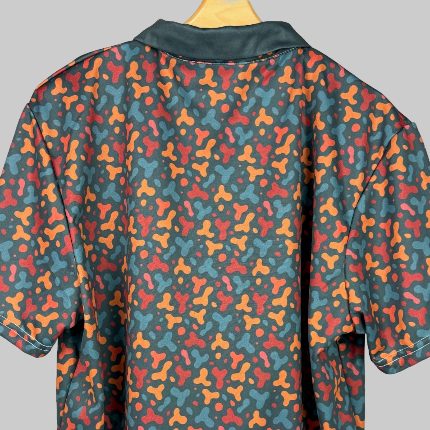 Colorful patterned shirt on a wooden hanger against a white background