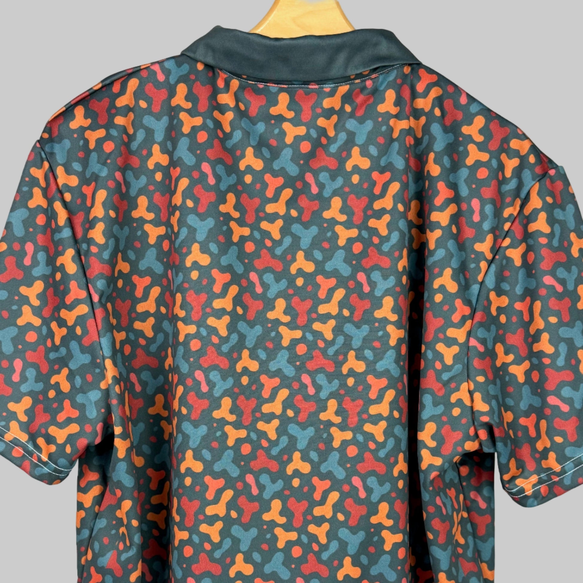 Colorful patterned shirt on a wooden hanger against a white background