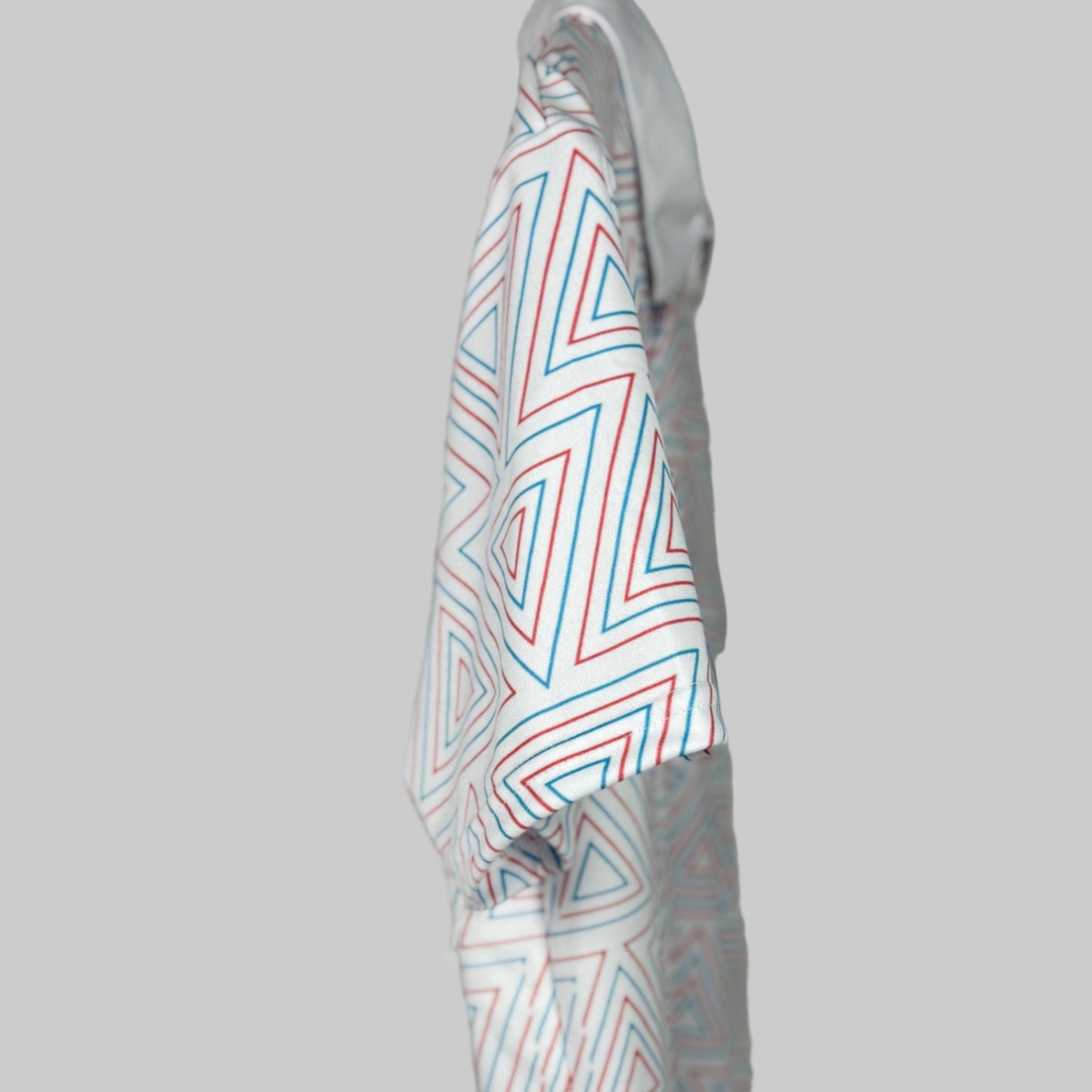 White shirt with red and blue geometric pattern on a gray background