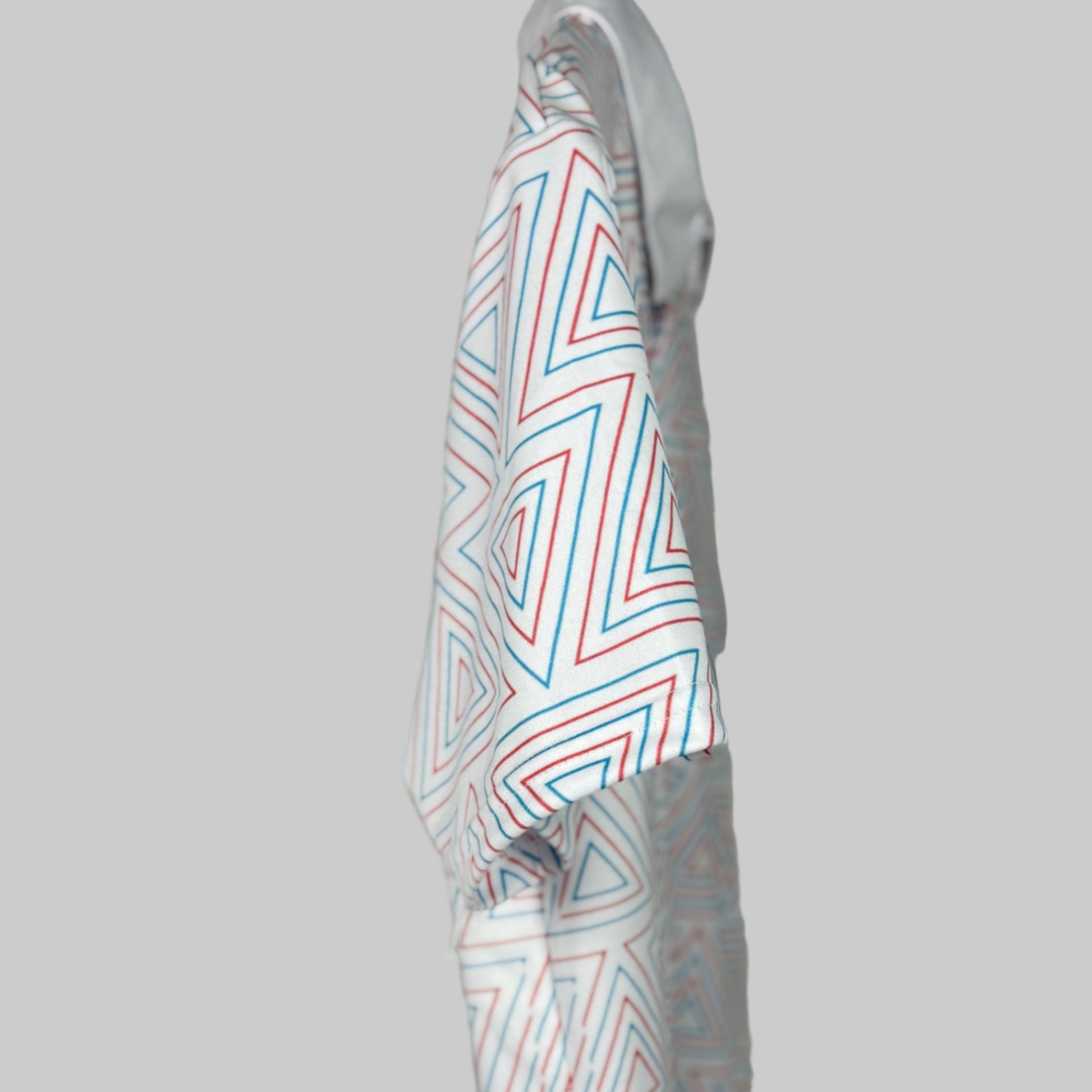 White shirt with red and blue geometric pattern on a gray background