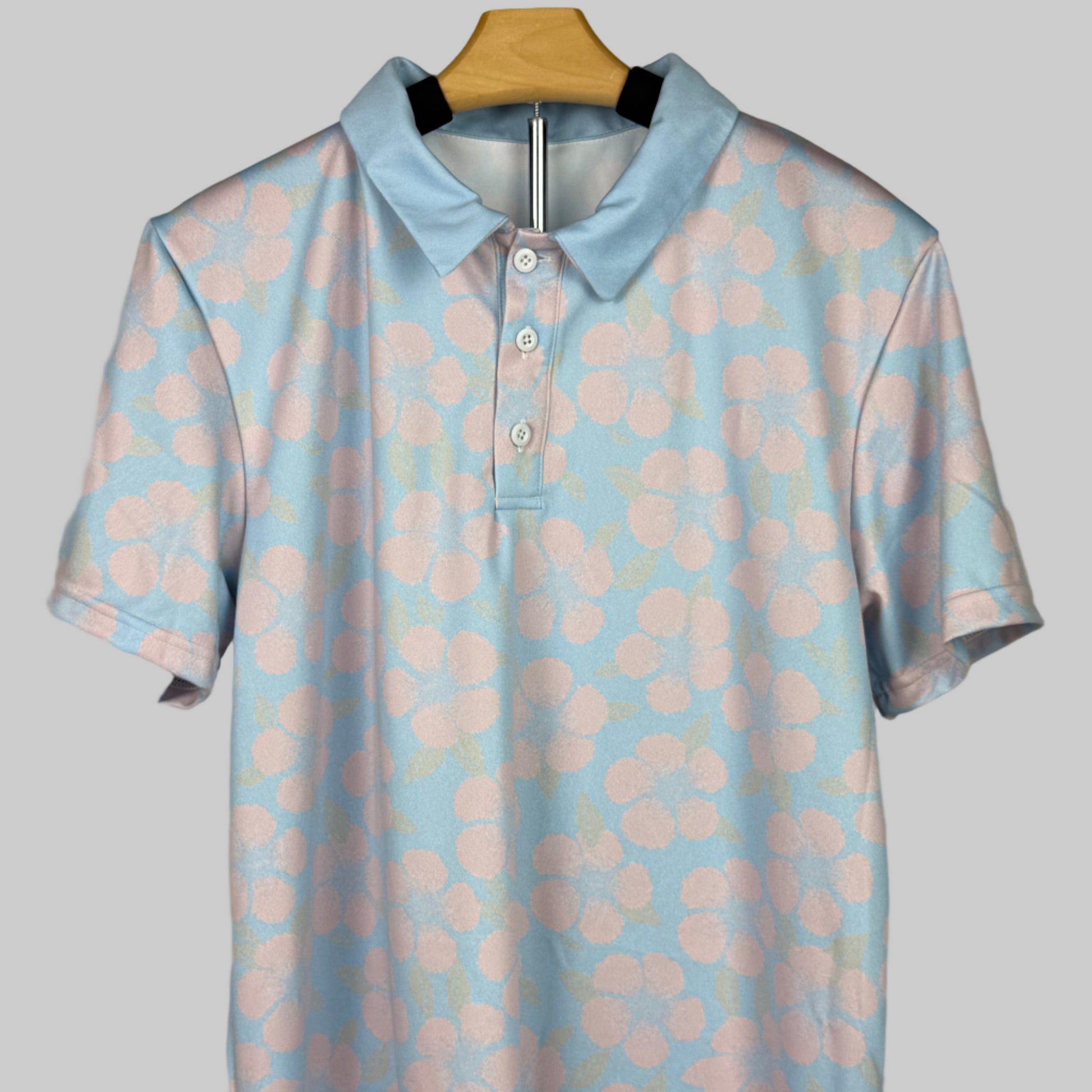 Light blue and pink patterned polo shirt on a hanger against a gray background