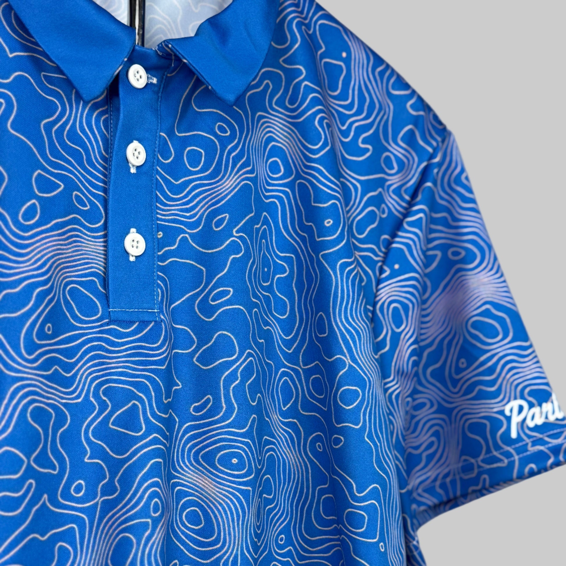 Blue polo shirt with white pattern on a plain background